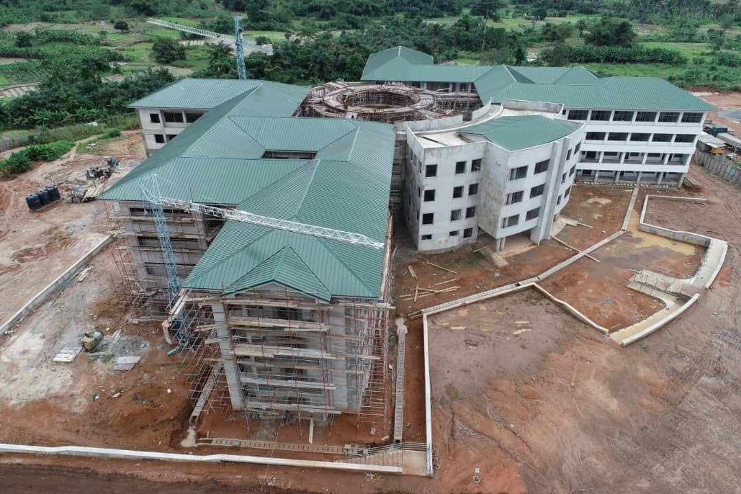 Aerial drone overview of multi-wing educational or commercial institutional complex with modern green hipped roofing and structural framing